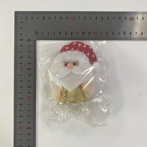 Detail of Christmas Santa gnome ornament with red plaid cloth in clear plastic packaging
