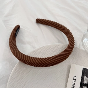 Macro detail of brown textured headband with spiral ribs on a neutral background