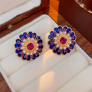 Detail view of blue enamel flower earrings with pink rhinestones and pearls in a jewelry box