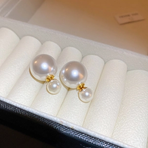 Macro detail of elegant double pearl earrings with gold metal bar in a white jewelry box