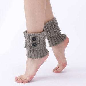 Detail of grey cable-knit leg warmers with decorative black buttons for winter