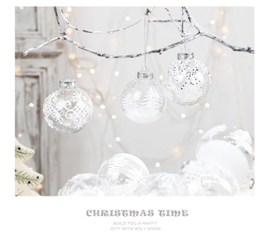 Close-up of clear 8cm Christmas ball with white snowflakes and stars on snowy branch