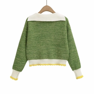 Green knit sweater with white lapel collar and yellow wavy trim on wooden hanger
