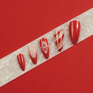Unghie natalizie a pressione con glitter rossi, fiocchi di neve e motivi di caramelle