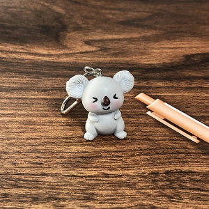 Close-up of a cute gray resin koala keychain with silver ring on a dark wood background