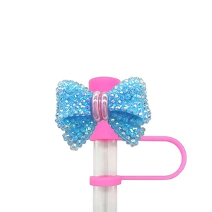 Detailed view of pink silicone straw cover with a sparkling blue rhinestone bow topper
