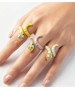 Detailed view of enamel snake rings with gold plating and zircons on a model's hand