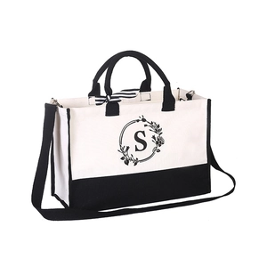 White canvas tote bag with black trim and floral letter S print and a striped bow