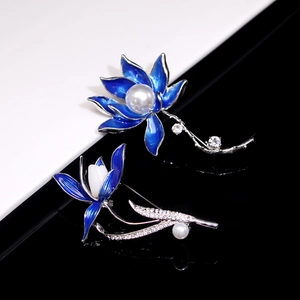 Detailed close-up of two elegant blue floral brooches with pearls and crystals