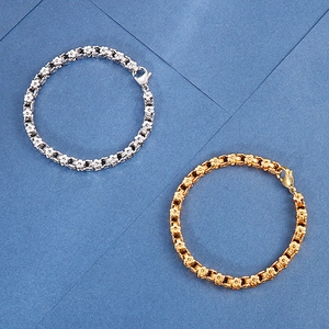 Detail of silver and gold flower link bracelets with lobster clasps on blue background