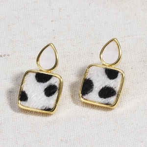 Detail of leopard print square drops and gold metal white teardrop earrings on fabric