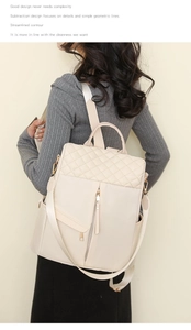 Detail of cream white quilted nylon backpack showing adjustable straps and multi-pocket design
