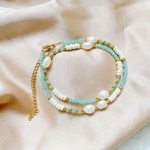 Close-up of baroque pearls and green crystal beads on premium champagne silk fabric