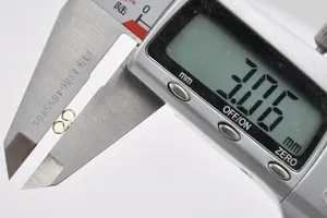 Digital caliper measuring the 3.06mm width of a golden butterfly earring back closure