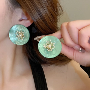 Élégantes boucles d'oreilles pétales vertes avec perles et zircons sur un modèle