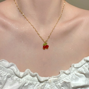 Close-up of a sweet cherry pendant necklace with red beads on a golden chain