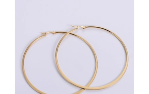 Detailed close-up of polished gold-plated titanium steel hoop earrings on a white background