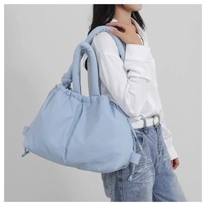 Detail of light blue nylon tote bag with drawstring closure and soft padded shoulder strap