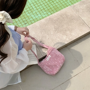 Dettaglio della borsa a spalla in velluto a coste rosa a pois con etichetta di marca