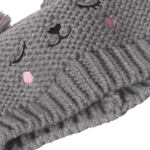 Detail of grey knitted hat featuring cute cat face embroidery and soft double pom-poms