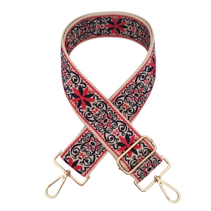 Close-up of ethnic floral embroidery handbag strap with golden metal clips and buckle