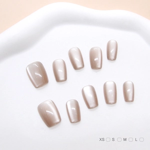 Detailed view of handmade cat-eye press-on nails in champagne pearl finish on white tray