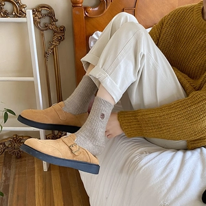 Detail of grey cotton ribbed mid-calf socks with floral embroidery and khaki suede mules