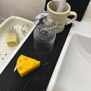 Large black silicone drying mat for kitchen cups and tableware on a white countertop