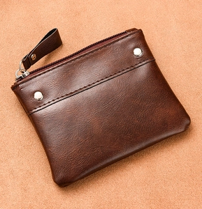 Macro detail of dark brown pebble leather wallet showing metal zipper and silver rivets