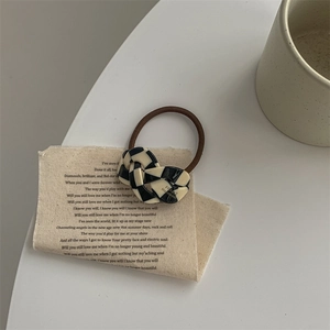Detail of checkered acetate hair tie with elastic band on vintage fabric background
