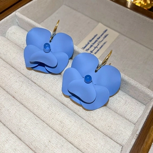 Detail of blue matte mesh flower earrings resting in a beige velvet jewelry box