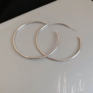 Macro detail of large polished silver hoop earrings with a sleek minimalist round design