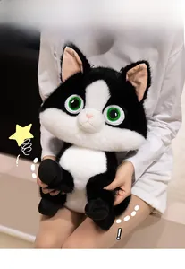 Close-up of a plush black and white cat doll with green eyes being held by a model