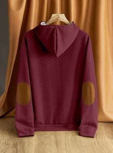 Dettaglio felpa con cappuccio bordeaux con motivo trapuntato a rombi e toppe sui gomiti