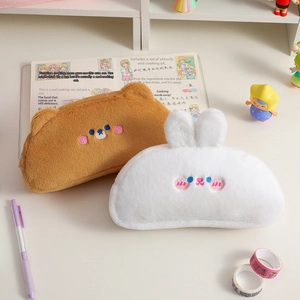 Close-up of cute plush bear and rabbit pencil cases on a cozy desk with stationery