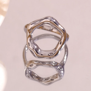 Macro detail of a silver irregular wavy ring with a polished mirror finish on a warm background