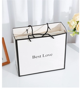 Detailed view of a white minimalist paper gift bag featuring Best Love text and black handles