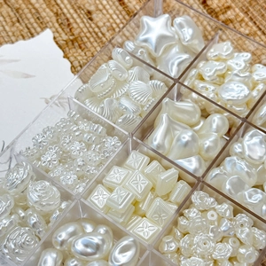 Macro shot of assorted pearl beads including stars and shells in a clear organizer box