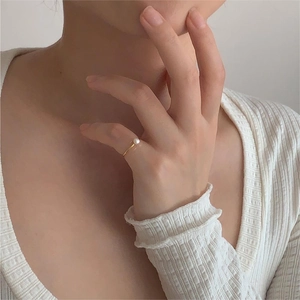 Close-up of minimalist gold pearl ring worn on hand with elegant knitwear background