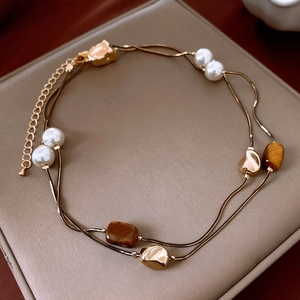 Détail d'un collier double rang avec œil de tigre et perles sur support en cuir beige