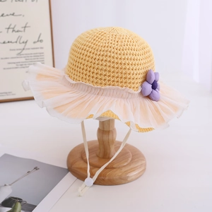 Detail of yellow knit sun hat with lace ruffle brim and purple flower accent for girls