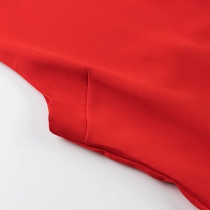 Macro view of bright red knit fabric texture and fine stitching detail on the mini dress