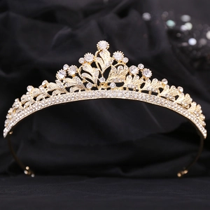 Detail of golden Baroque crown with clear rhinestones on black velvet background