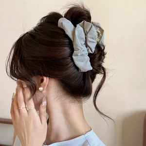 Grey pleated fabric hair claw clip for elegant styling shown on a model hair side view