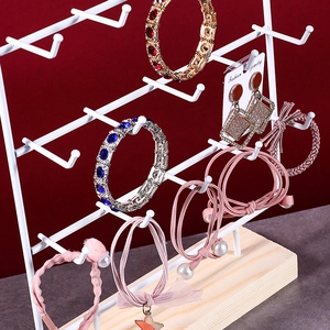 Detail of white metal jewelry organizer with hooks and solid wooden base display