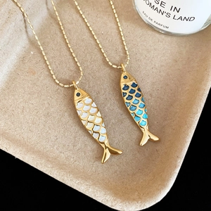 Detailed macro view of enamel fish pendants with golden beads on textured tray