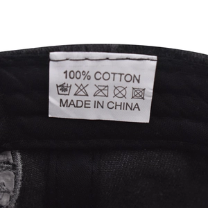 Detail view of the 100% cotton wash care label and fabric texture on a black baseball cap