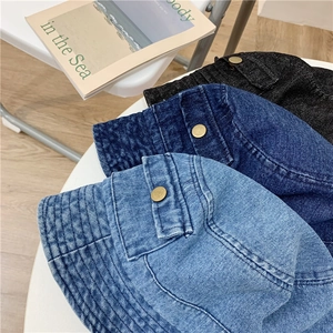 Detail of washed denim bucket hats in light blue, dark blue and black with metal buttons