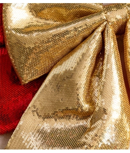 Macro view of glittering gold and red sequin Christmas bow decorations with pearl cotton