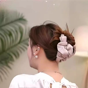 Rear view of a model wearing a champagne pleated cloud hair claw clip in a bun